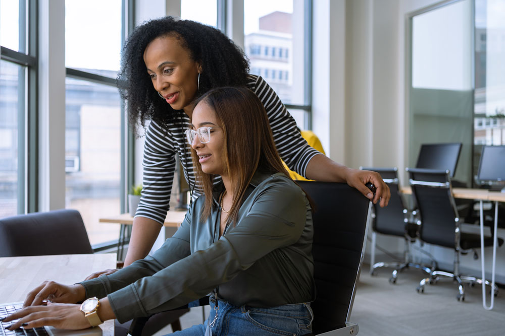Two women focusing on a project on a laptop.
