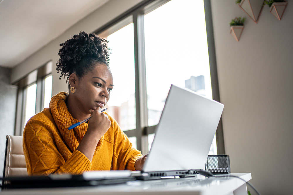 Woman working on a laptop in a bright office.