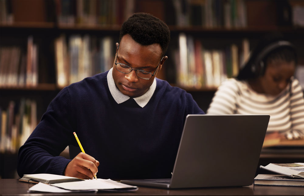 Focused student writing at a library table