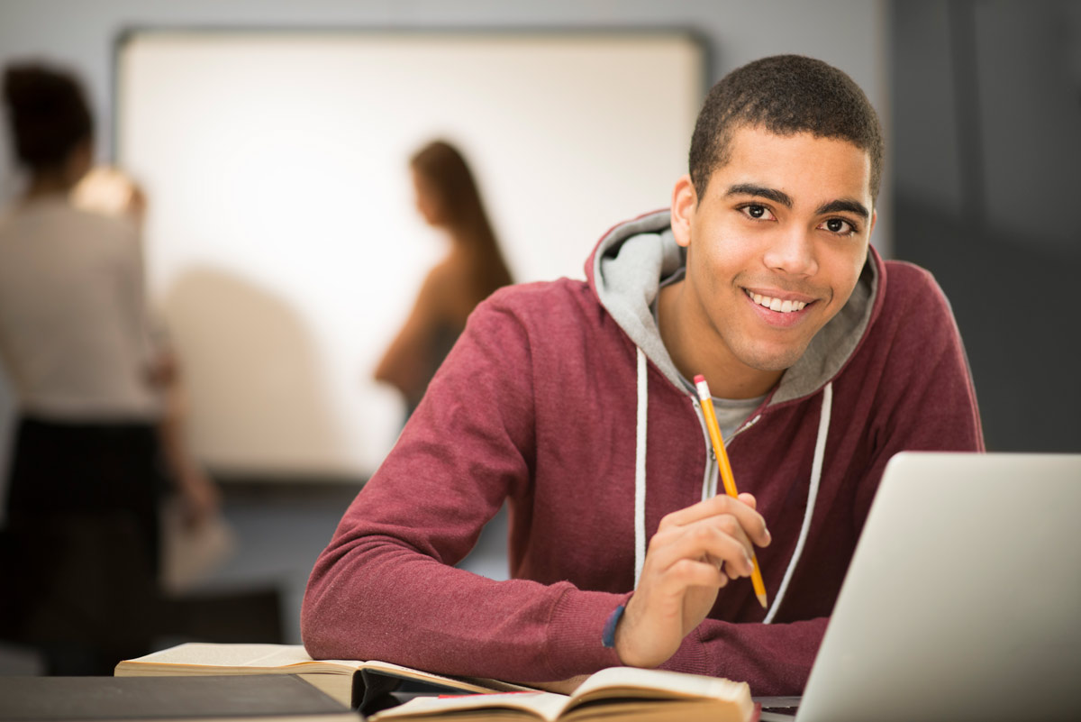 Student studying with laptop and books.